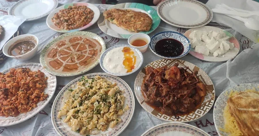 مائدة مغطاة بأطباق صغيرة من المأكولات البحرينية والخبز والمغموسات